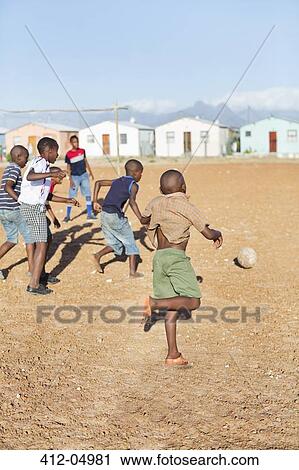 Boys playing soccer together in dirt field View Large Photo Image Stock Image - Boys playing soccer together in dirt field. Fotosearch