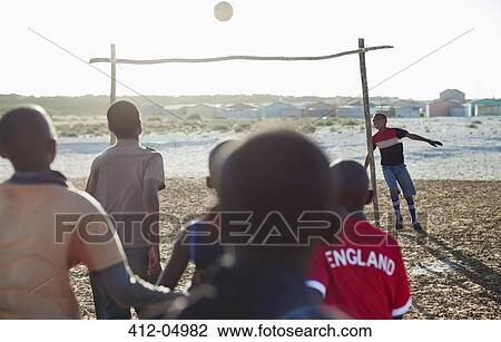 Boys playing soccer together in dirt field View Large Photo Image Stock Image - Boys playing soccer together in dirt field. Fotosearch
