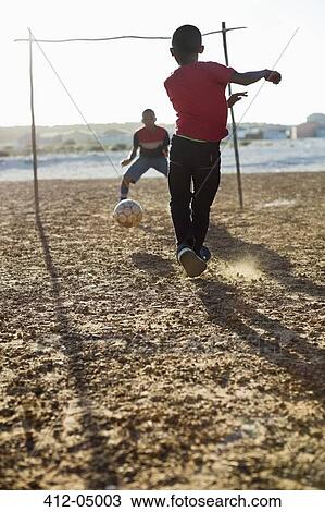Boys playing soccer together in dirt field View Large Photo Image Stock Image - Boys playing soccer together in dirt field. Fotosearch