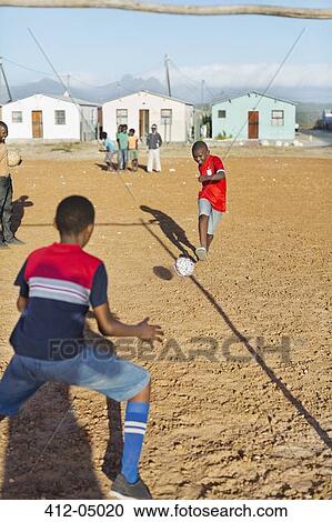 Boys playing soccer together in dirt field View Large Photo Image Stock Image - Boys playing soccer together in dirt field. Fotosearch