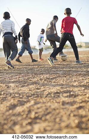 Boys playing soccer together in dirt field View Large Photo Image Stock Image - Boys playing soccer together in dirt field. Fotosearch