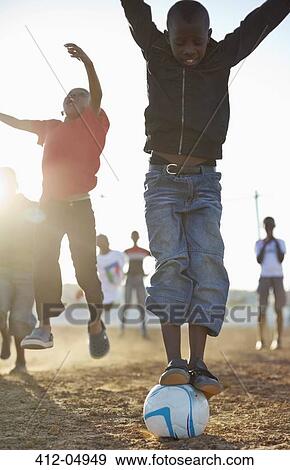 Boys playing soccer together in dirt field View Large Photo Image Stock Photo - Boys playing soccer together in dirt field. Fotosearch