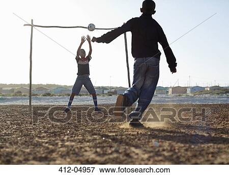 Boys playing soccer together in dirt field View Large Photo Image Stock Photo - Boys playing soccer together in dirt field. Fotosearch