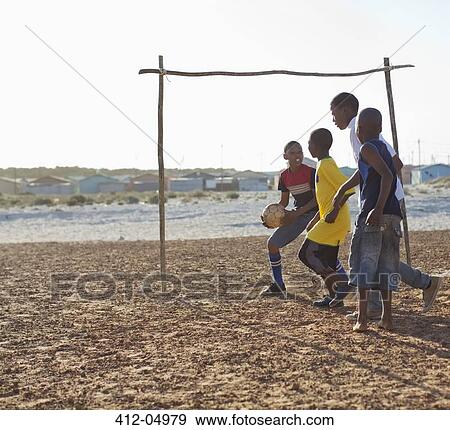Boys playing soccer together in dirt field View Large Photo Image Stock Photo - Boys playing soccer together in dirt field. Fotosearch