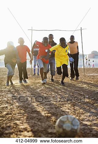 Boys playing soccer together in dirt field View Large Photo Image Stock Photo - Boys playing soccer together in dirt field. Fotosearch