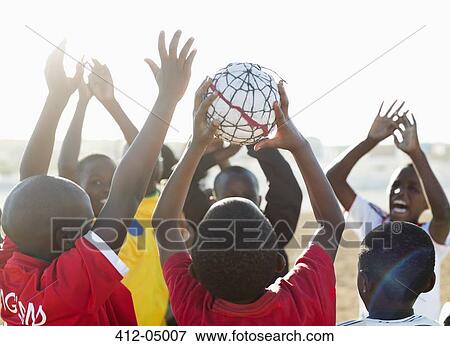 Boys playing soccer together in dirt field View Large Photo Image Stock Photo - Boys playing soccer together in dirt field. Fotosearch