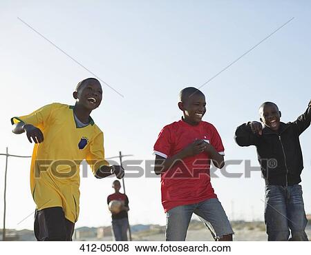 Boys playing soccer together in dirt field View Large Photo Image Stock Photo - Boys playing soccer together in dirt field. Fotosearch