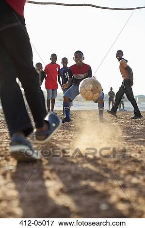 Boys playing soccer together in dirt field View Large Photo Image Stock Photo - Boys playing soccer together in dirt field. Fotosearch