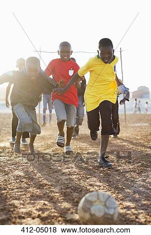 Boys playing soccer together in dirt field View Large Photo Image Stock Photo - Boys playing soccer together in dirt field. Fotosearch