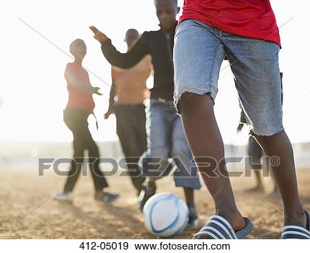 Boys playing soccer together in dirt field View Large Photo Image Stock Photo - Boys playing soccer together in dirt field. Fotosearch