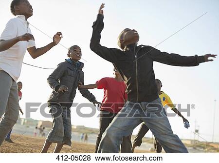 Stock Photo - Boys playing soccer together in dirt field. Fotosearch