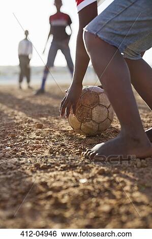 Boys playing soccer together in dirt field View Large Photo Image Stock Photograph - Boys playing soccer together in dirt field. Fotosearch