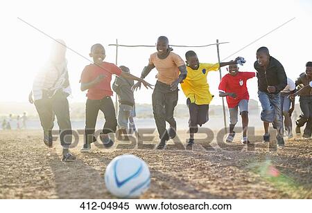 Boys playing soccer together in dirt field View Large Photo Image Stock Photography - Boys playing soccer together in dirt field. Fotosearch
