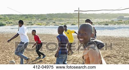 Stock Photography - Boys playing soccer together in dirt field. Fotosearch