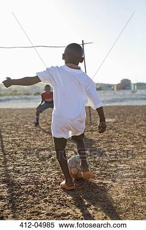 Boys playing soccer together in dirt field View Large Photo Image Stock Photography - Boys playing soccer together in dirt field. Fotosearch