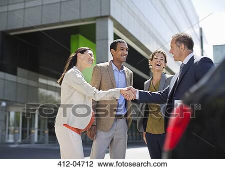 Stock Image - Business people shaking hands outdoors. Fotosearch
