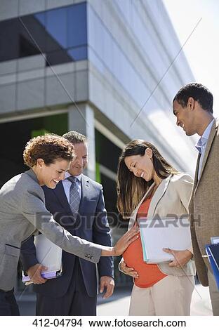Picture - Businesswoman holding pregnant colleague's bell. Fotosearch