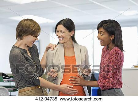 Stock Photography - Colleagues admiring pregnant businesswoman's bell. Fotosearch