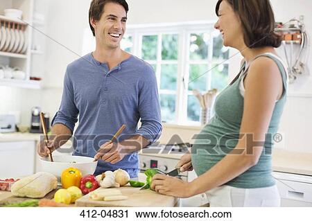 Stock Image - Couple cooking together in kitchen. Fotosearch
