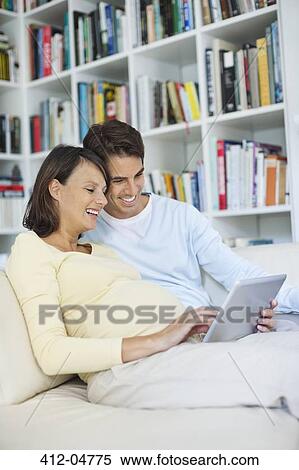 Stock Photography - Couple using tablet computer on sofa. Fotosearch