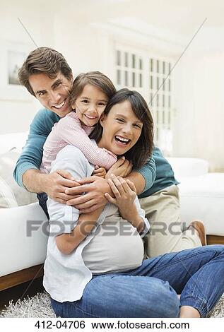 Family hugging in living room View Large Photo Image Stock Photograph - Family hugging in living room. Fotosearch