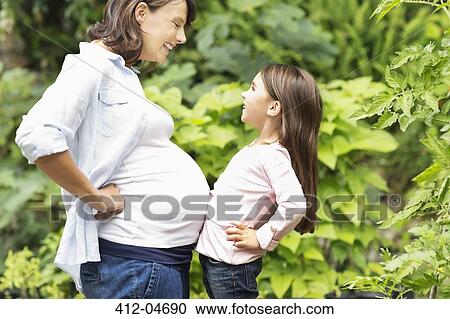 Girl bumping pregnant mother's bell View Large Photo Image Stock Image - Girl bumping pregnant mother's bell. Fotosearch