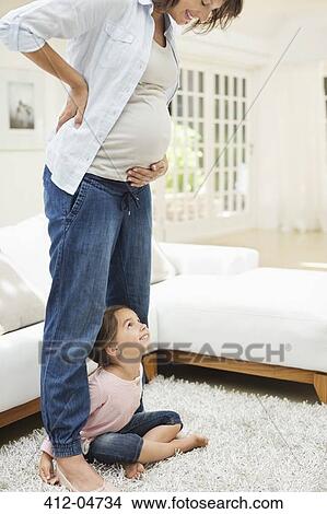 Picture - Girl holding pregnant mother's leg. Fotosearch
