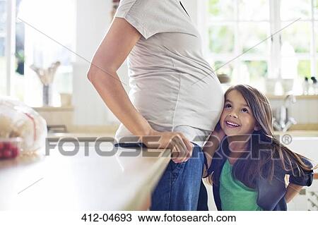 Stock Image - Girl listening to pregnant mother's bell. Fotosearch