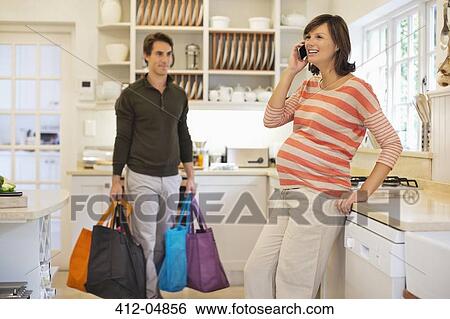 Stock Photograph - Man carrying bags for pregnant girlfriend. Fotosearch