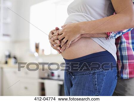 Picture - Man holding pregnant girlfriend's bell. Fotosearch