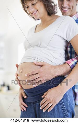 Stock Photo - Man holding pregnant girlfriend's bell. Fotosearch