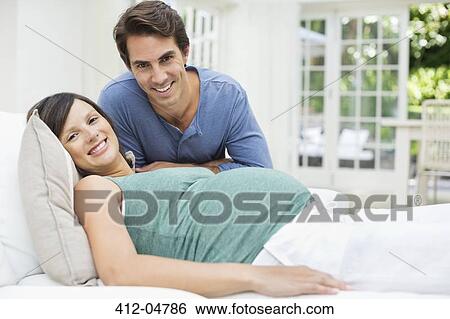 Man sitting next to pregnant woman resting on bed View Large Photo Image Stock Photograph - Man sitting next to pregnant woman resting on bed. Fotosearch