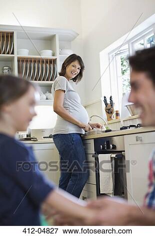 Stock Photo - Pregnant mother cooking in kitchen. Fotosearch