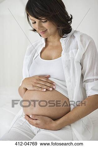 Stock Photo - Pregnant woman holding her belly. Fotosearch