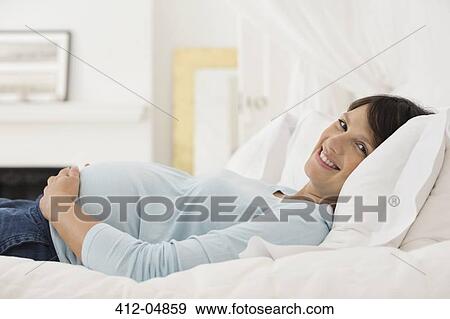 Pregnant woman laying on bed View Large Photo Image Stock Photo - Pregnant woman laying on bed. Fotosearch