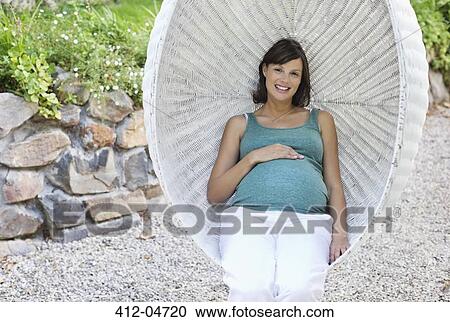 Stock Image - Pregnant woman relaxing outdoors. Fotosearch