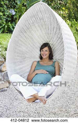 Stock Image - Pregnant woman relaxing outdoors. Fotosearch