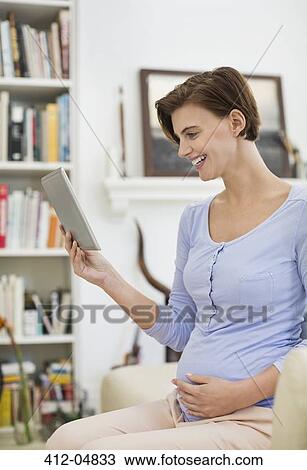 Stock Image - Pregnant woman using tablet computer. Fotosearch