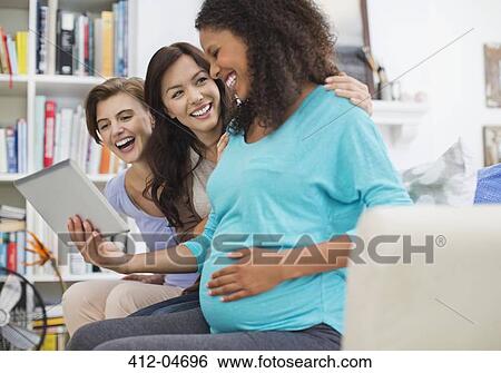 Pregnant woman using tablet computer with friends View Large Photo Image Stock Photograph - Pregnant woman using tablet computer with friends. Fotosearch