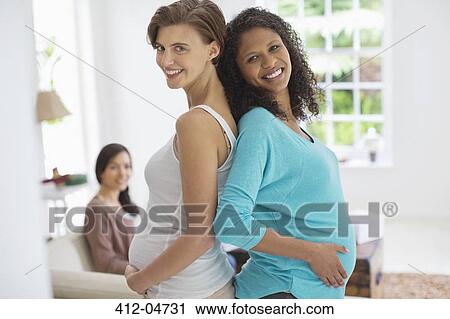 Stock Image - Pregnant women smiling together. Fotosearch