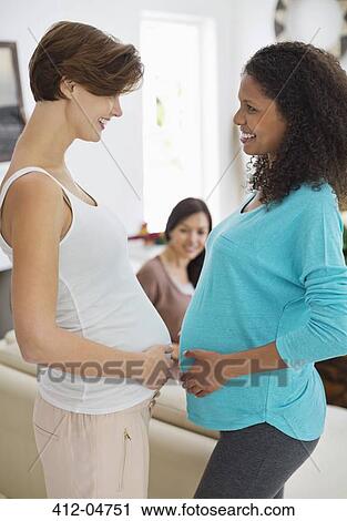 Stock Image - Pregnant women touching bellies. Fotosearch
