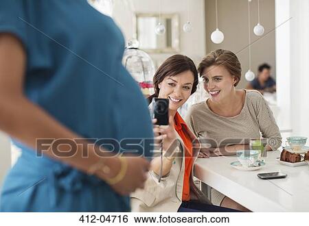 Stock Photograph - Women taking pictures of pregnant friend. Fotosearch