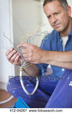 Electrician examining wires in kitchen View Large Photo Image Stock Photo - Electrician examining wires in kitchen. Fotosearch
