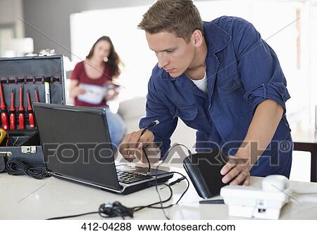 Stock Photo - Electrician using laptop in home. Fotosearch