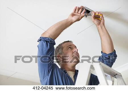 Stock Photography - Electrician working on ceiling lights. Fotosearch