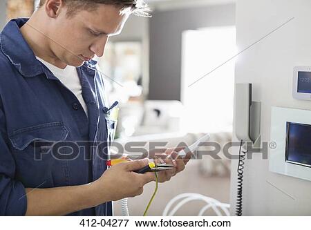 Stock Photo - Electrician working on telephone in home. Fotosearch