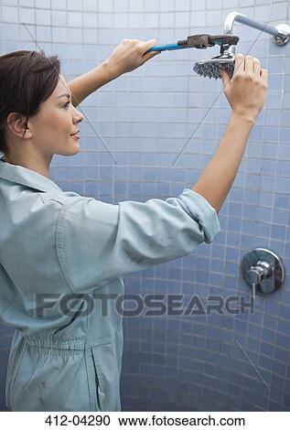 Female plumber working on shower head in bathroom View Large Photo Image Stock Image - Female plumber working on shower head in bathroom. Fotosearch