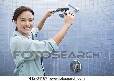 Stock Photo - Female plumber working on shower head in bathroom. Fotosearch