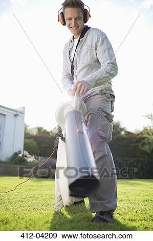 Man blowing leaves in backyard View Large Photo Image Stock Photo - Man blowing leaves in backyard. Fotosearch