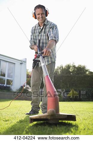 Man using weed whacker in backyard View Large Photo Image Picture - Man using weed whacker in backyard. Fotosearch